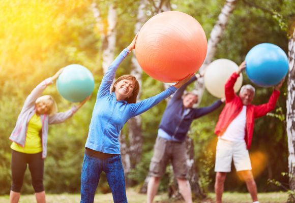 Teilnehmer an einem Präventionskurs im Freien, die gemeinsam Übungen zur Förderung der Gesundheit durchführen, umgeben von Natur.